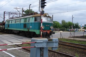 Autor - Zbigniew Dominiak. Zdjęcie przedstawia wjeżdżający pociąg towarowy na przejazd kolejowy przy ulicy Młyńskiej w Kościanie. Godz. 12.41